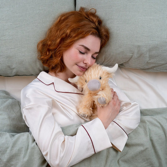 Marmalade the weighted plush being cuddled in bed. 