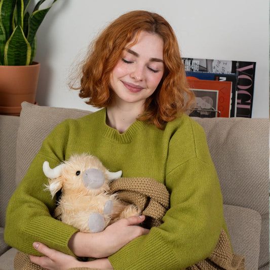 Adult using a weighted Highland cow on their lap for grounding and deep pressure stimulation.